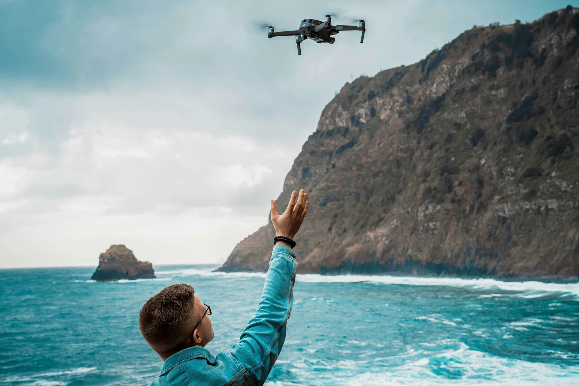 A drone racer launches a drone on a scenic coastline. Private equity consulting firms can help drone racing businesses reach new heights.