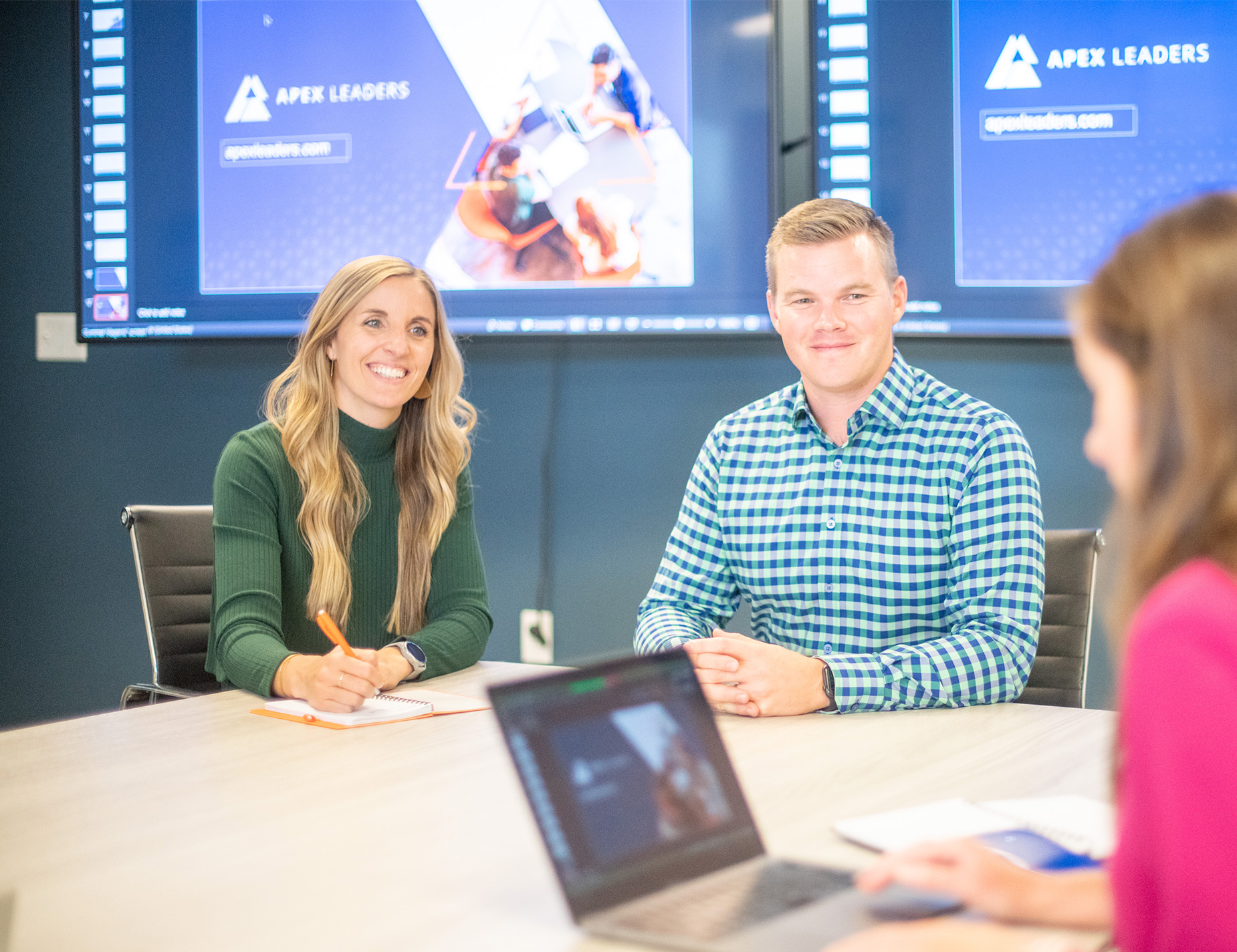 Team meeting at Apex Leaders, a leader in private equity consulting services, with two professionals smiling and collaborating.