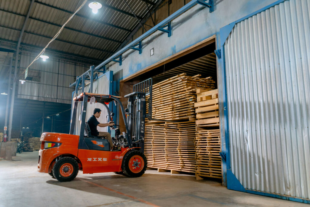 A stack of wooden pallets is moved by a utility vehicle for reuse, a competitor for the plastic pallet industry.