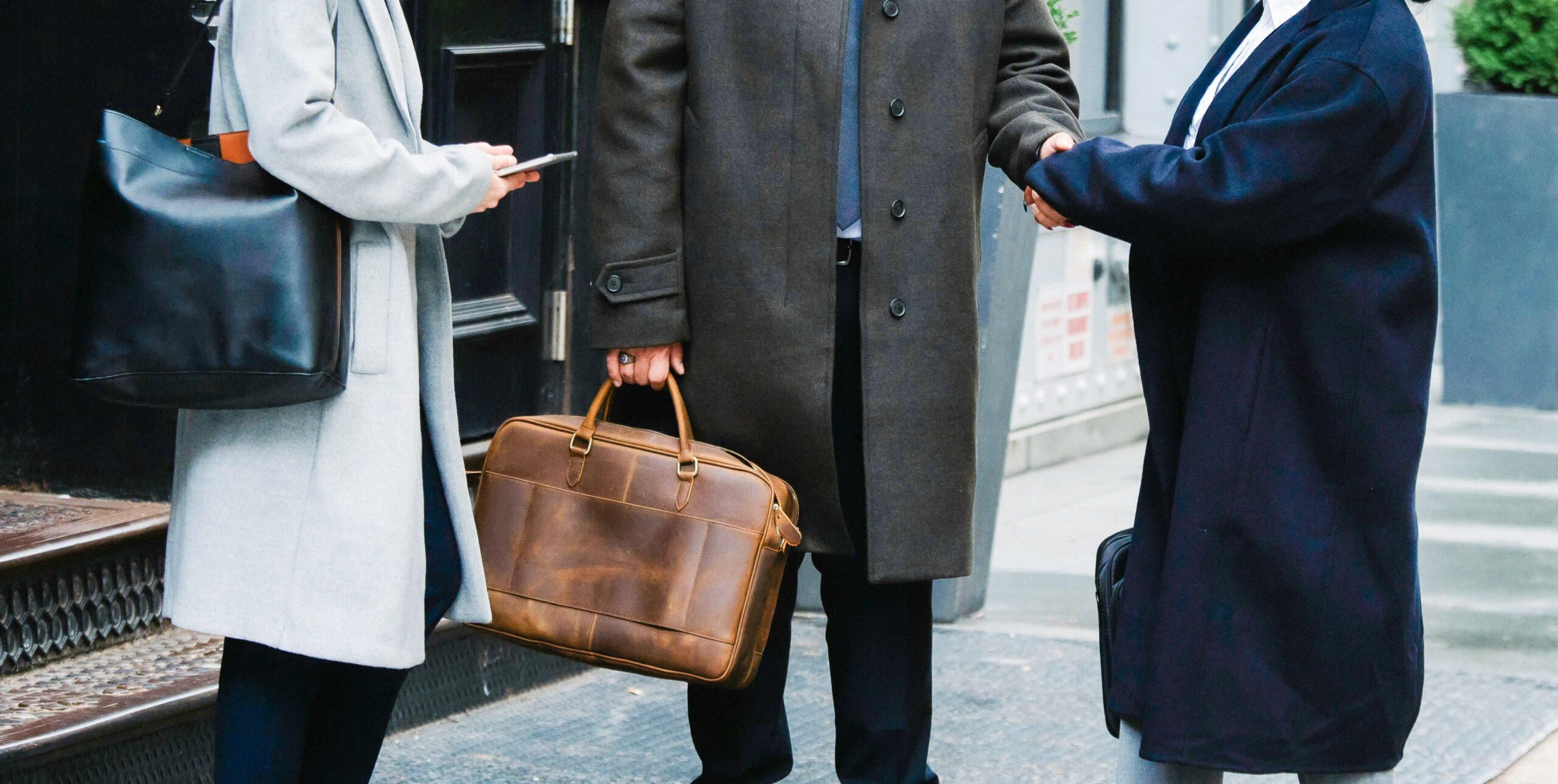 Two industry experts shake hands with an investor during board of directors recruitment.