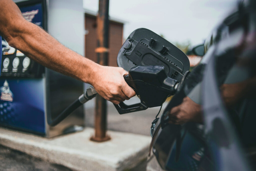 A close-up of a person pumping gas at a gas station pump—one of the reasons renewable energy investment remains important.