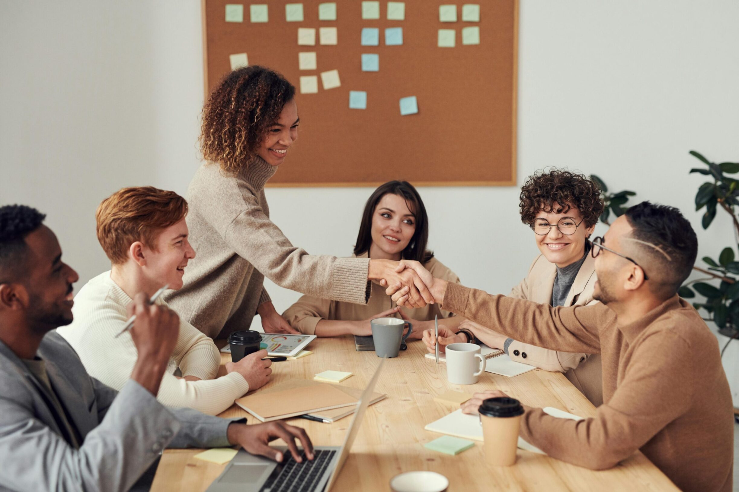 A group happily collaborates on private equity portfolio management around a table.