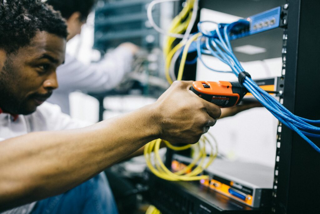 An engineer repairing obsolete technology with tools in a warehouse.