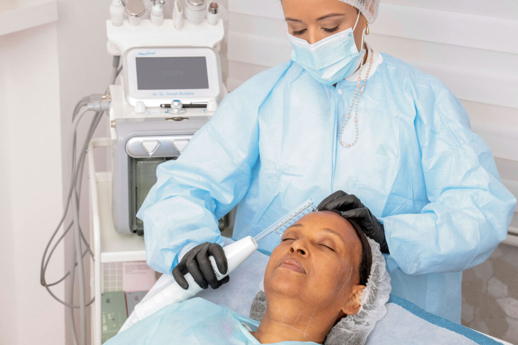 A medspa professional begins a facial treatment on a relaxed patient.