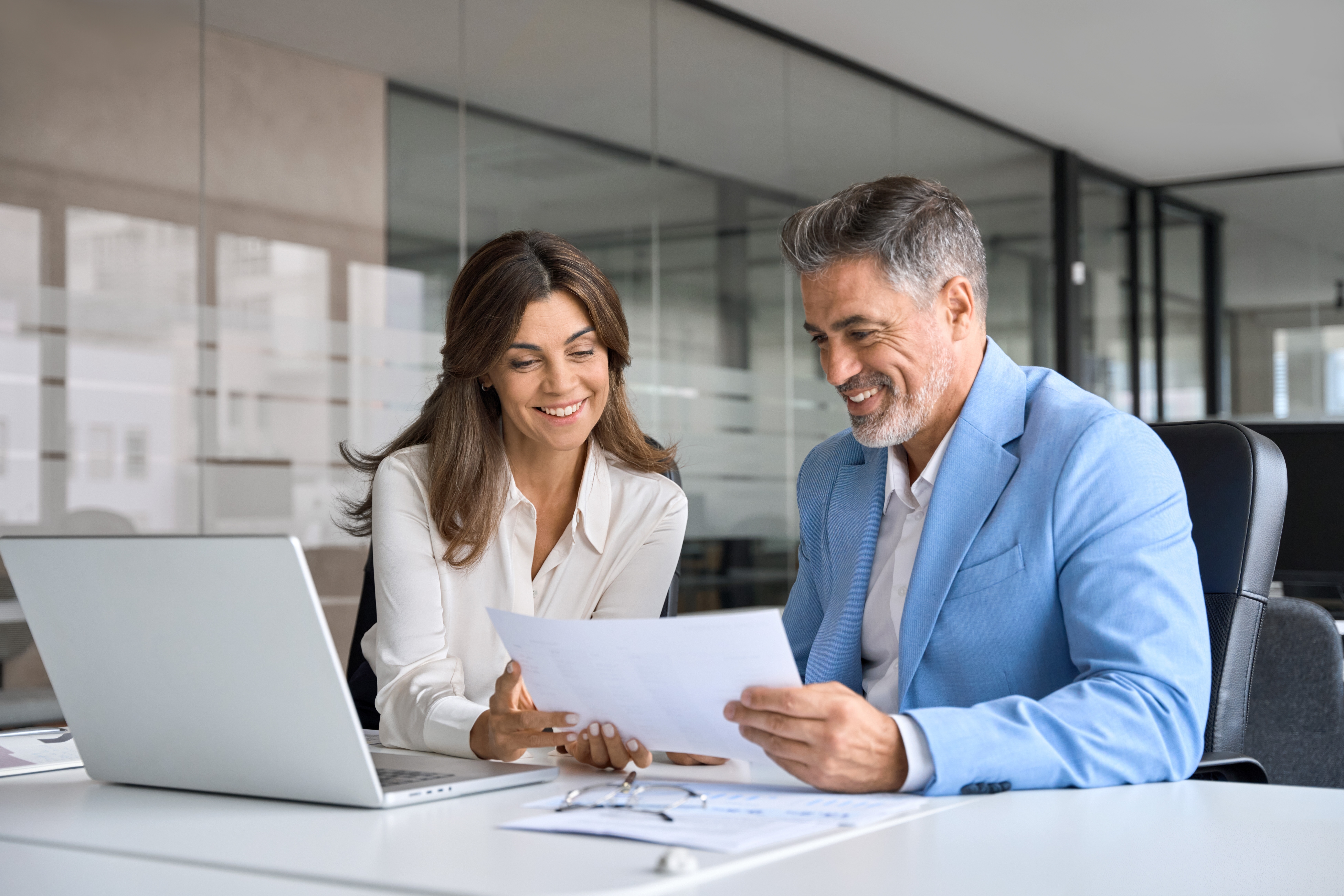 A man and woman review due diligence documents on laptop