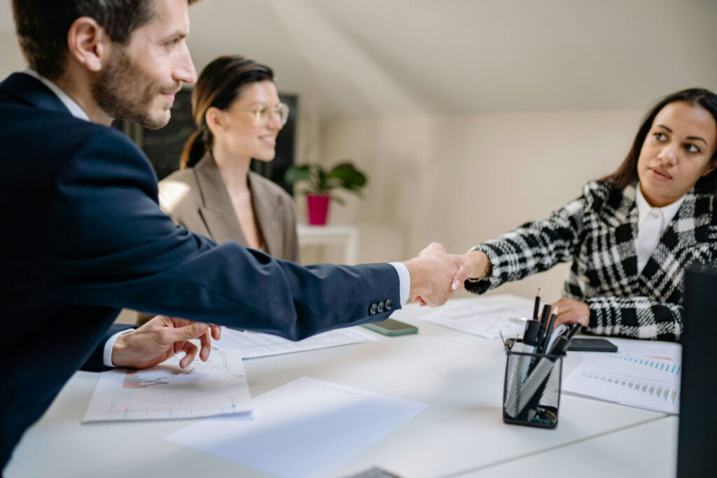 Private equity professionals shaking hands at a table after conducting due diligence.