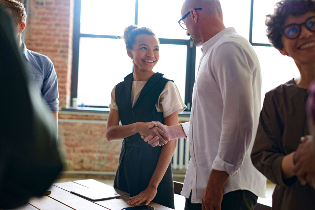 Private equity team members exchange handshake, symbolizing expert insights and due dilligence.